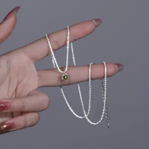 Close-up detail of the sparkling sterling silver chain with a green zircon pendant on hand.
