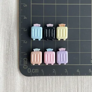 Detailansicht kleiner Koffer-Harz-Cabochons zur Größenvorführung in bunten Bastel-Farben.