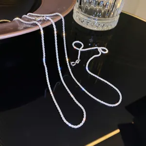 Detailed shot of sparkling silver clavicle chain necklace, delicate shimmering texture closeup.