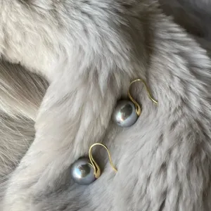 Detailed close-up shot of elegant grey pearl earrings with delicate gold hooks.