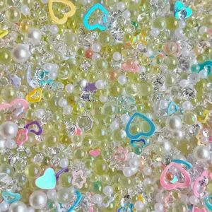 Mixed DIY craft accessories including bubble beads, pearls, rhinestones, and heart charms for slime.