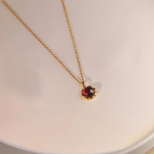 Primer plano detallado de un elegante collar con colgante de piedra roja vintage limpia.