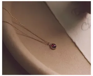 Primer plano de un delicado collar con colgante de granate vintage en una bandeja.