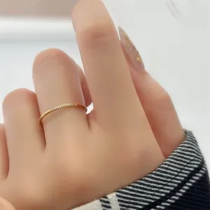 Primer plano detallado de un elegante anillo dorado delgado con circonitas en dedo.