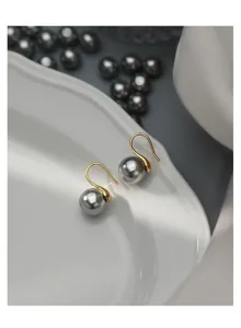 Detail shot of grey pearl hook earrings on white dish, elegant jewelry close-up view.