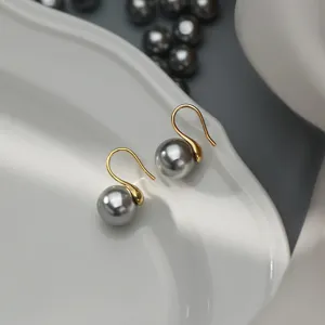 Close-up detail of elegant grey pearl hook earrings with sterling silver finish on white dish.