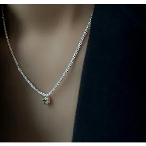 Sterling silver sparkling necklace detail with olive green zircon pendant, elegant jewelry.