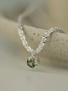 Close-up detail of sterling silver starlight chain with olive green zircon pendant sparkle.
