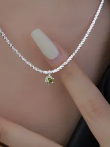 Close-up detail of sterling silver shimmering chain necklace with green zircon gemstone pendant.