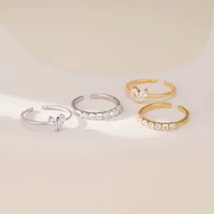Primer plano detallado de anillos apilables plateados y dorados con pavé de circón y corazon.