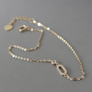 Gold-plated silver bracelet detail featuring a paved geometric pendant and delicate chain link.