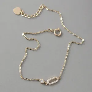 Close-up detail of dainty 14k gold plated sterling silver bracelet with sparkling zircon charms.