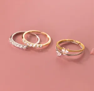 Primer plano de anillos de plata S925 apilables con cristales brillantes y detalles de corazón.