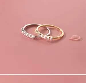 Primer plano de anillos abiertos apilables de circonita en plata y oro, detalle elegante.