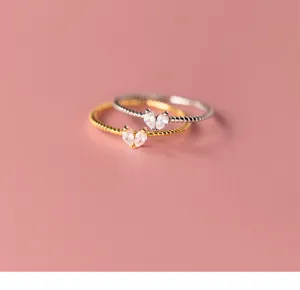 Primer plano detallado de anillos apilables de plata y oro con circonitas de corazón.