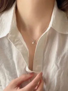Primer plano detallado de un delicado collar con colgante de perlas de plata en la clavícula.