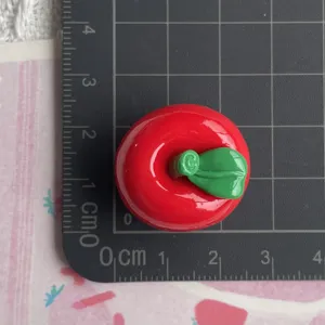 Dettaglio in primo piano di cabochon in resina mela rossa charm artigianale DIY per cover.