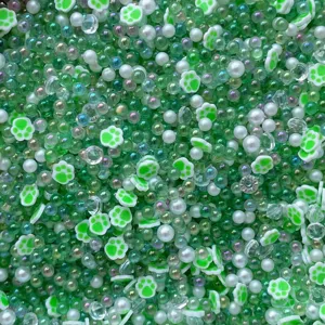 Green polymer clay cat paw beads mixed with translucent bubble beads and pearls for DIY crafts.