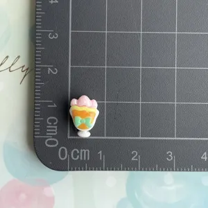 Resin ice cream sundae charm with bow DIY craft accessory miniature size reference view.