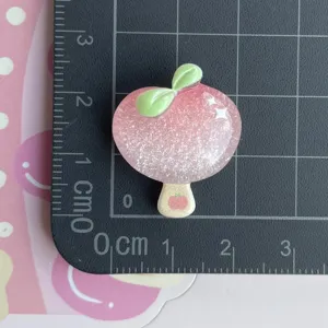 Primo piano di un ciondolo in resina rosa glitterato con foglie verdi per accessori fai-da-te.