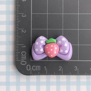 Close-up detail of cute purple bow resin strawberry craft accessory, DIY handmade item.