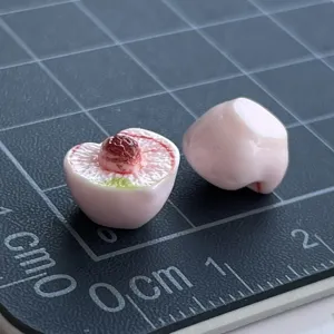 Dettaglio ciondolo pesca in resina in miniatura, cibo finto carino per cover telefono diy.