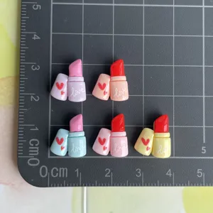 Primo piano dettaglio di cabochon in resina mini rossetto con stampa per decorazioni fai-tec.