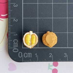 Primo piano di ciondoli durian in resina in miniatura con texture e dimensioni su griglia.