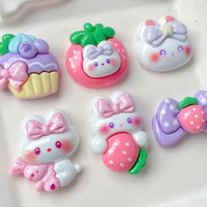 Close-up detail of cute cartoon resin bunny, cake and strawberry cabochons for DIY crafts.