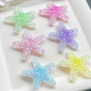 Vue detaillee de petits accessoires en resin, etoiles de mer pailletees, belles.