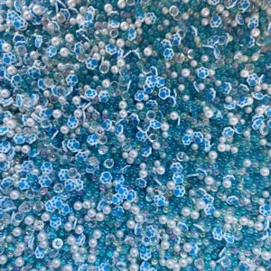 Detailed close-up view of mixed blue white paw beads, pearls and rhinestones for DIY crafts.