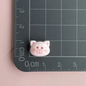 Close-up detail of cute pink pig resin cabochon charm for DIY nail art and hair accessories.