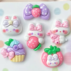 Close up of cute resin cartoon bunny and strawberry cabochons for DIY crafts and jewelry.