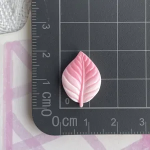 Vista de cerca de un accesorio de resina en forma de hoja rosa con detalles finos y venas muy claras.