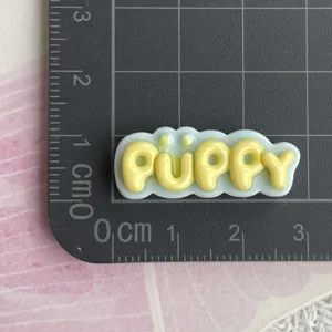 Primo piano dettagliato del ciondolo lettera puppy in resina gialla e blu per custodia.