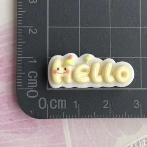 Dettaglio ciondolo lettera hello in resina, cabochon cartone per fermaglio e cover telefono