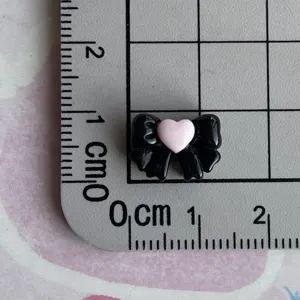 Mini black resin bow charm with pink heart for DIY phone case and hair clip decoration.