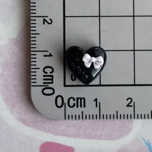 Resin black heart charm with pink bow and love text detail view for DIY phone case decor
