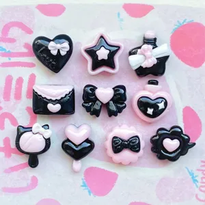 Closeup of cute black and pink resin charms, bow and heart DIY accessories for phone case.