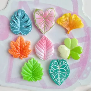 Cabujones de resina de hoja colorida en detalle, dijes de plantas para fundas de teléfono.