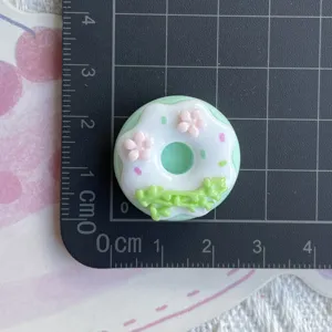 Detailed shot of cute green donut resin charm DIY craft accessory for phone case decoration.