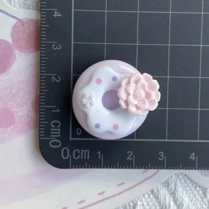 Close up detail view of the cute resin donut charm with pink flower, shown with size measure.