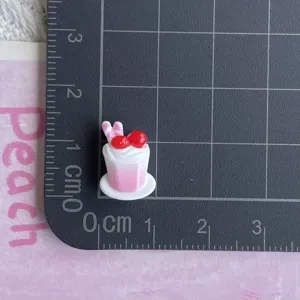 Dettaglio in primo piano del ciondolo per torta in resina in miniatura sulla griglia.