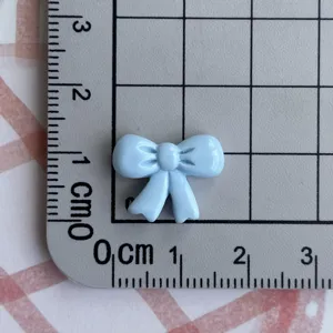 Mini light blue resin bow charm detail view showing actual product size on measurement grid.