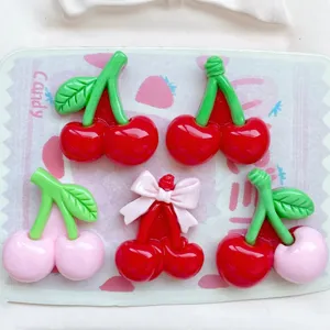Close-up detail of cute resin cherry charms with bows, perfect for DIY phone case and hairpin crafting.