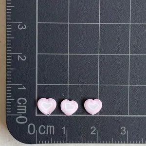 Vue détaillée de pendentifs cœur en argile polymère rose avec taille sur tapis quadrillé.