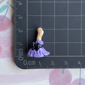 Close-up detail of purple witch legs resin charm with black bow for DIY hair clip decor.