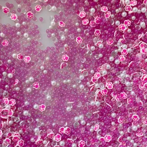 Mix of pink bubble beads, white pearls, and cute cat paw clay slices for DIY slime crafts.