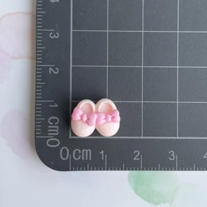 Detailaufnahme von Harz Babyschuh Cabochon mit rosa Schleife für DIY Handwerk Zubehör.
