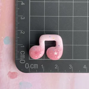 Close-up detail shot of cute pink star music note resin charm for DIY phone case decor.